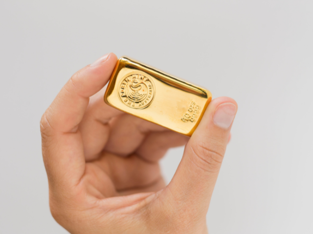 a hand holding a Perth Mint gold bar 