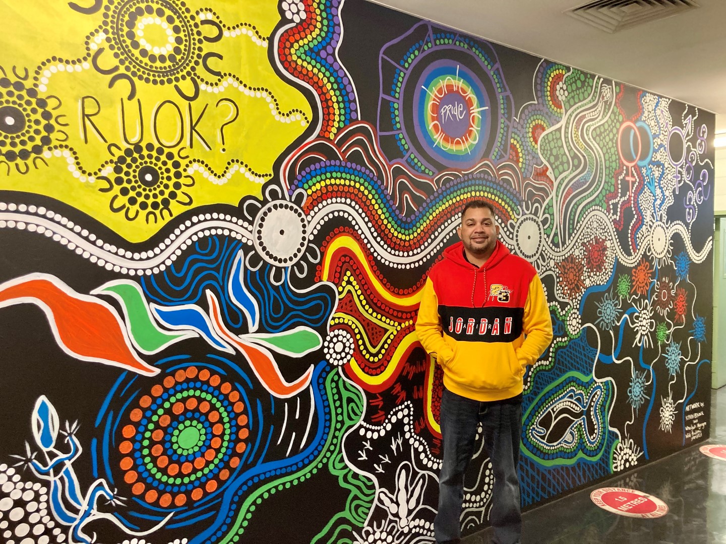 Indigenous artist Kevin Bynder in front of the Perth Mint's Refinery Indigenous mural  