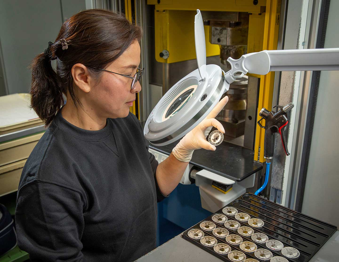 a Perth Mint employee inspecting a coin