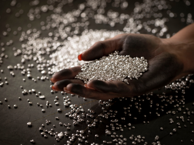 a female hand holding silver granules 