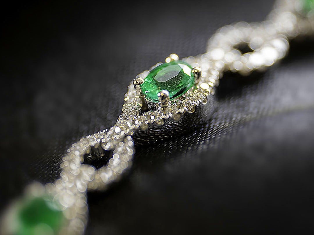 Emerald and diamond bracelet laying on a black cloth
