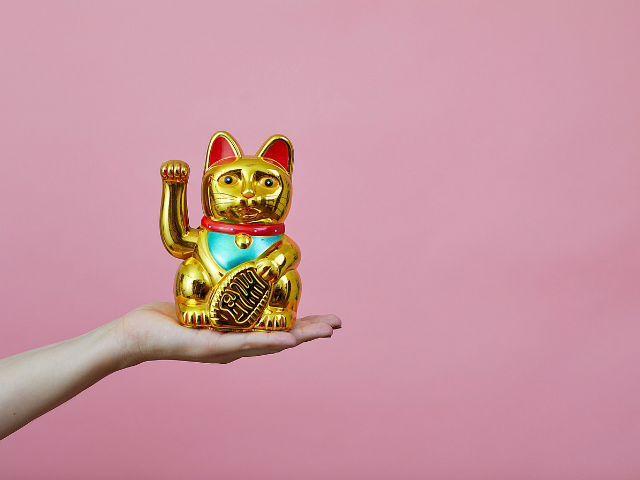 a hand holding a golden lucky cat 