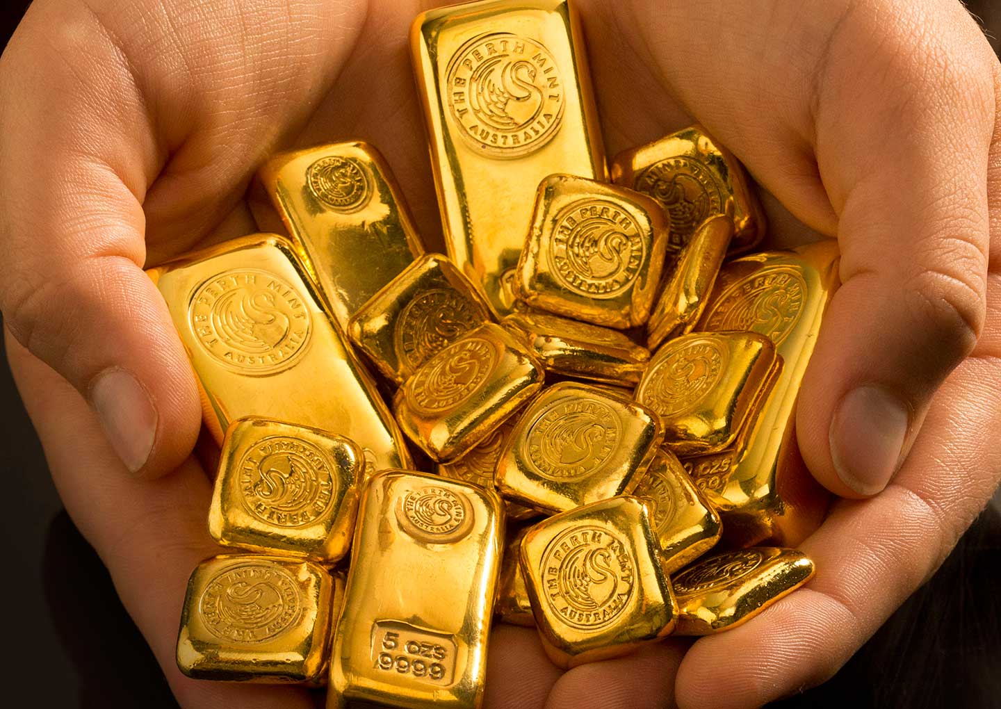 Mixed gold cast bars in hands at The Perth Mint.