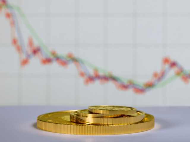 gold coins stacked in front of a line graph